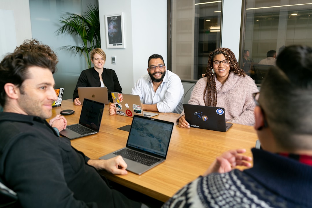 A B2B buying group meeting at a boardroom table reviewing data on laptops