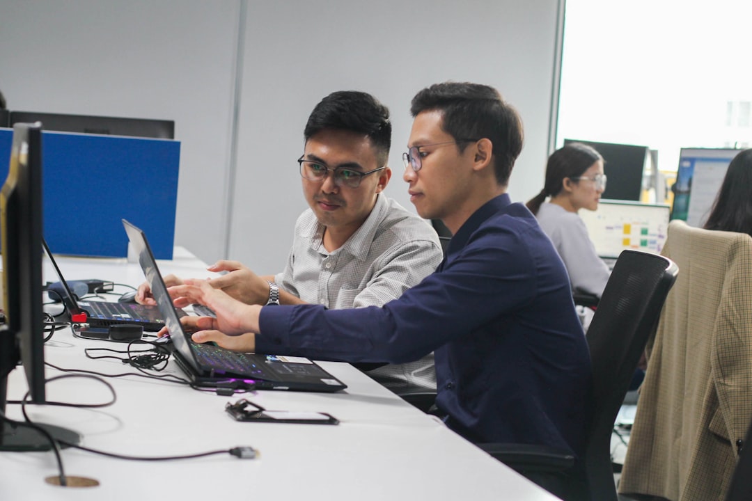 Two colleagues working together at a desk with computers
