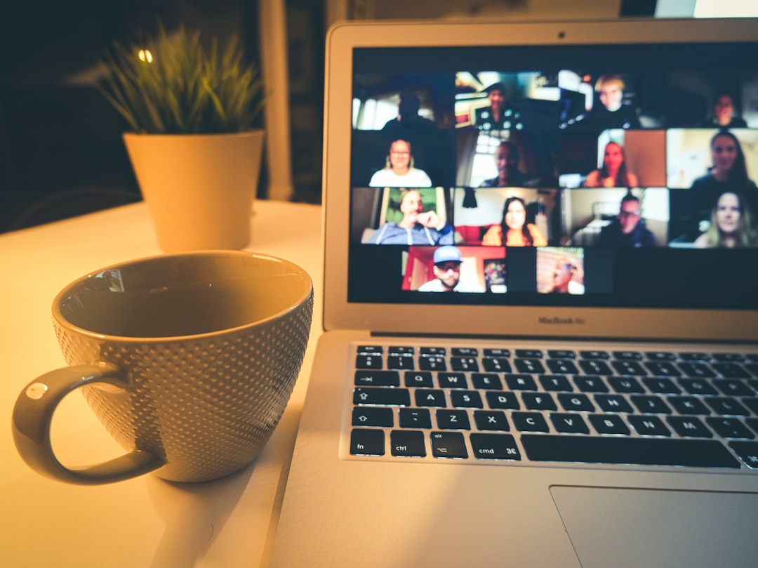 Laptop on a desk showing a video conference call with a grid of participants
